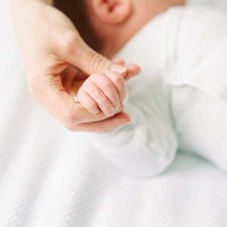 mom holding newborn baby sleeping hand