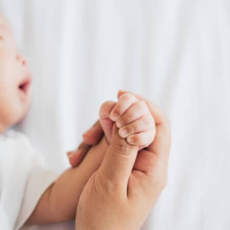newborn baby sleeping while mom holds hand